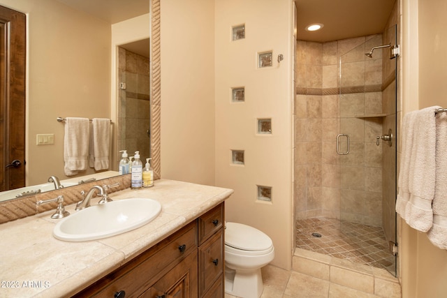 bathroom with vanity, toilet, a shower with shower door, and tile patterned flooring