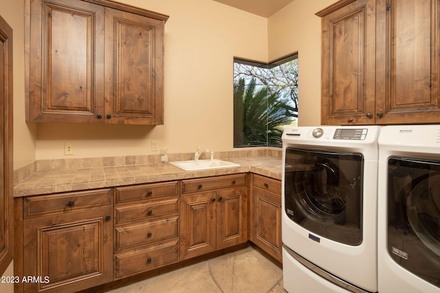 laundry room with sink, washing machine and dryer, and cabinets