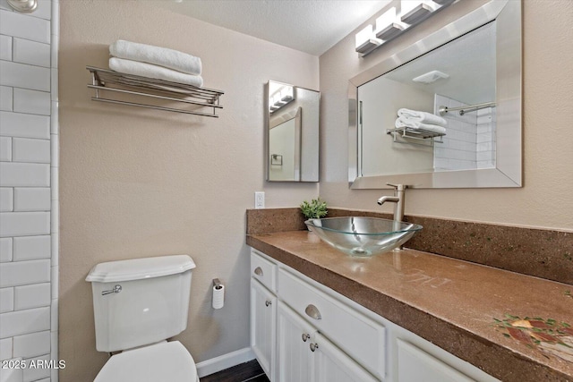 bathroom featuring vanity, a textured ceiling, toilet, and walk in shower