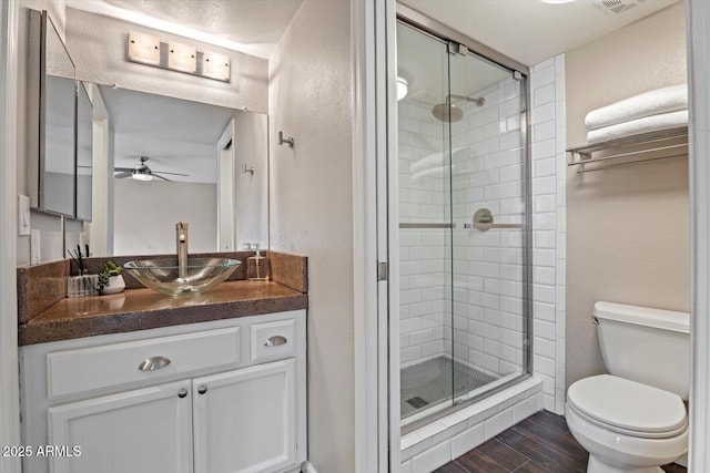 bathroom with walk in shower, ceiling fan, vanity, and toilet