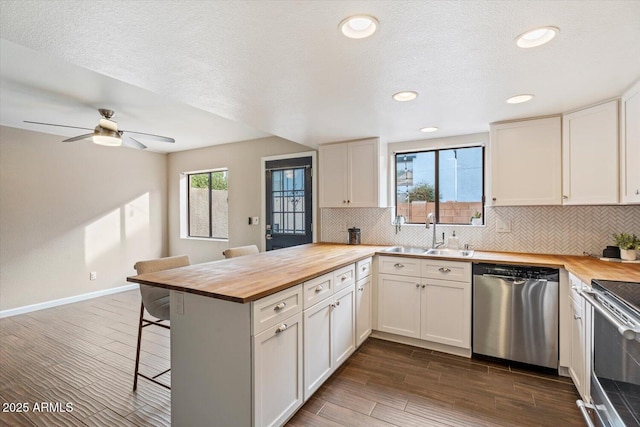 kitchen featuring wood counters, stainless steel appliances, sink, and white cabinets