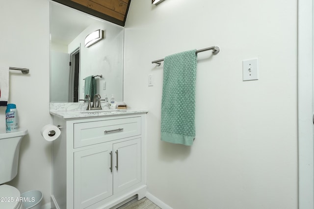 half bathroom featuring baseboards, toilet, and vanity