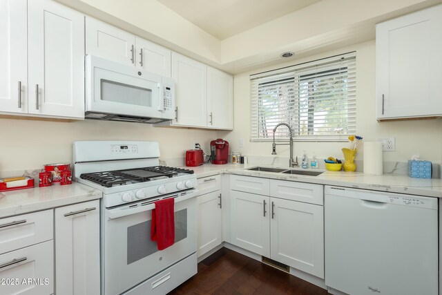 kitchen with a sink, white appliances, white cabinets, and dark wood-style flooring