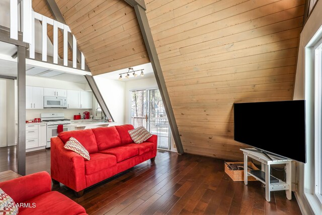 living area with wooden walls, lofted ceiling with beams, dark wood-type flooring, track lighting, and wood ceiling