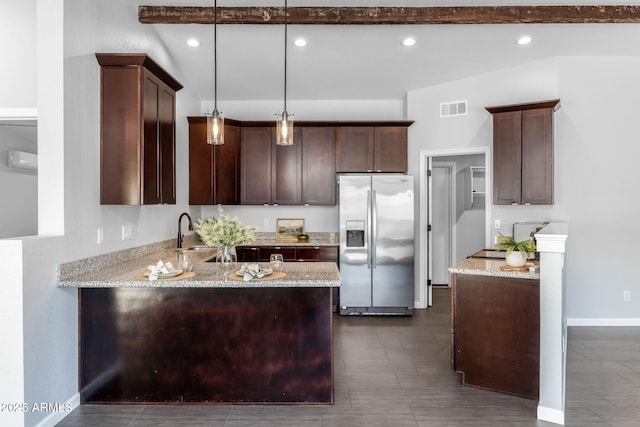 kitchen with stainless steel fridge, light stone counters, pendant lighting, and a sink