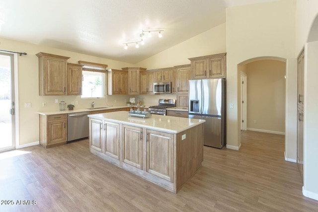 kitchen featuring light hardwood / wood-style floors, appliances with stainless steel finishes, sink, a kitchen island, and high vaulted ceiling