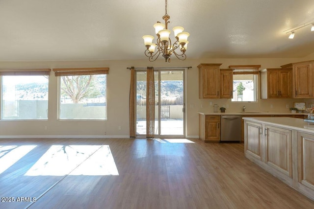 kitchen featuring light hardwood / wood-style flooring, dishwasher, hanging light fixtures, sink, and a chandelier