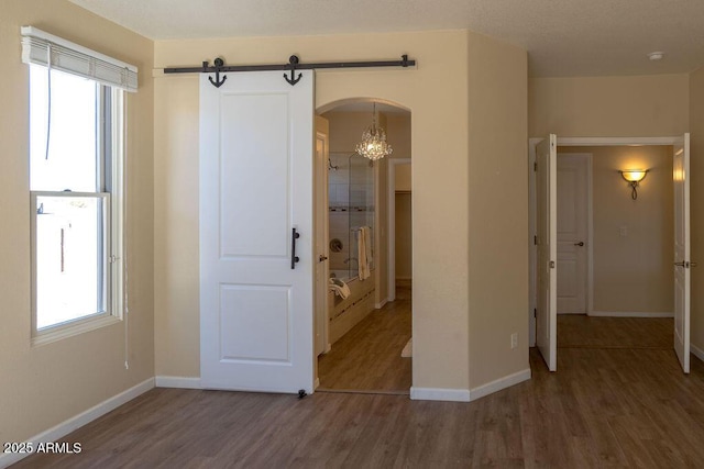 interior space featuring hardwood / wood-style flooring, ensuite bath, and a barn door