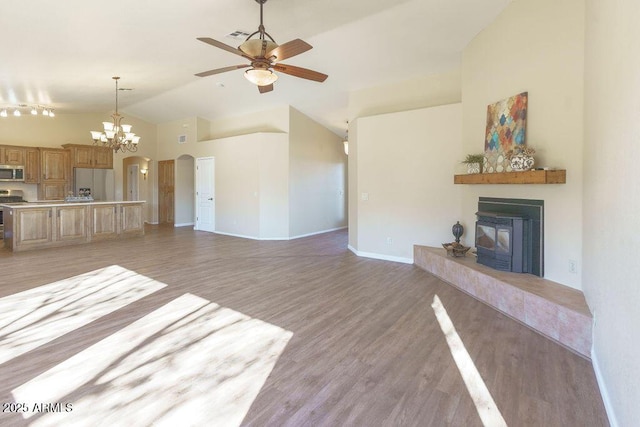 unfurnished living room with light hardwood / wood-style floors, ceiling fan with notable chandelier, and vaulted ceiling