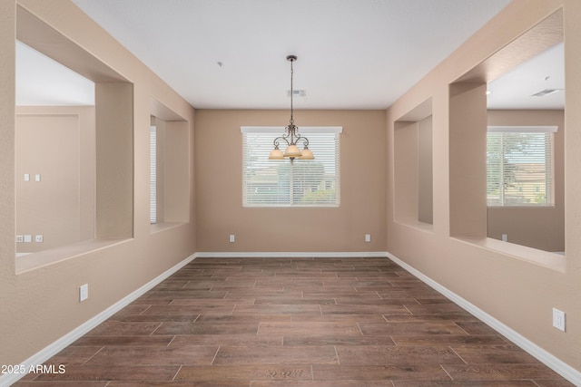 unfurnished dining area featuring dark wood-style floors, a notable chandelier, visible vents, and baseboards