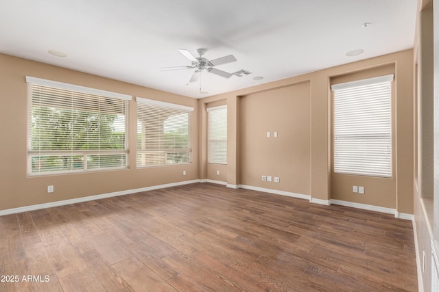 unfurnished room with visible vents, wood finished floors, a ceiling fan, and baseboards