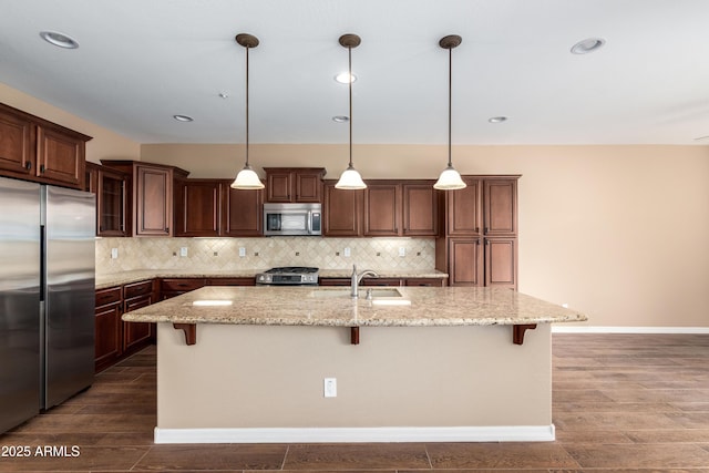 kitchen featuring backsplash, a breakfast bar area, stainless steel appliances, and a sink