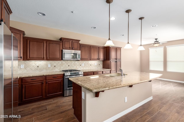 kitchen featuring stainless steel appliances, dark wood finished floors, a sink, and a kitchen bar