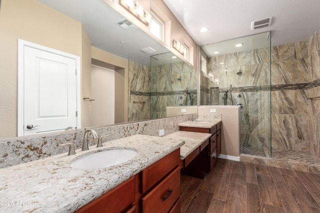 bathroom with vanity, visible vents, tiled shower, and wood finished floors