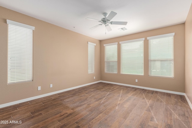 unfurnished room with baseboards, ceiling fan, visible vents, and wood finished floors