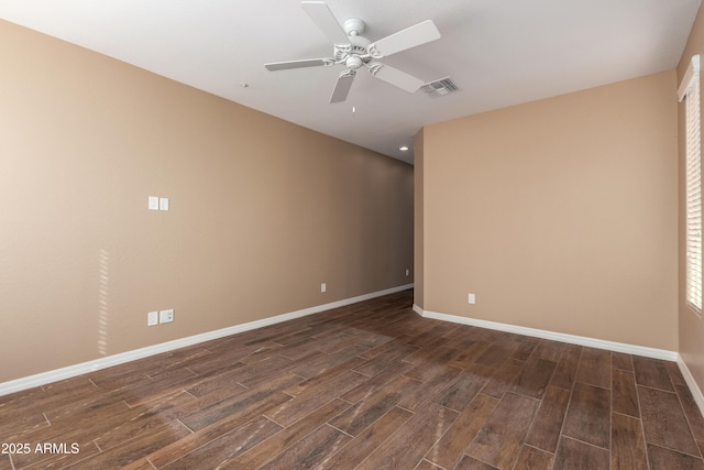 empty room with dark wood-type flooring, a ceiling fan, visible vents, and baseboards