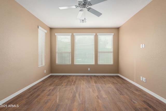 spare room with visible vents, ceiling fan, baseboards, and wood finished floors