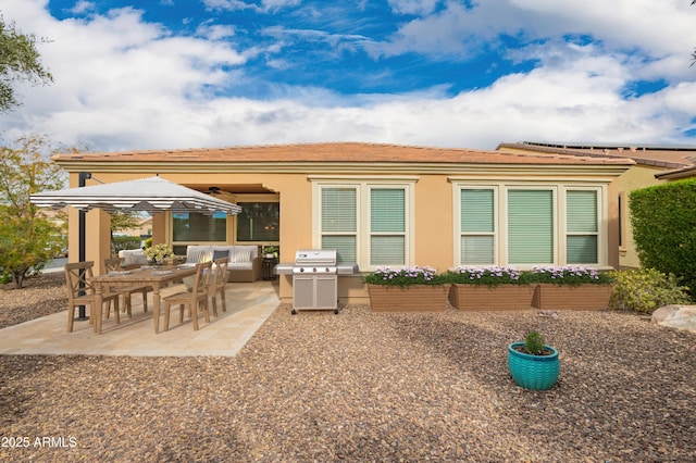 rear view of house with stucco siding, a tile roof, and a patio