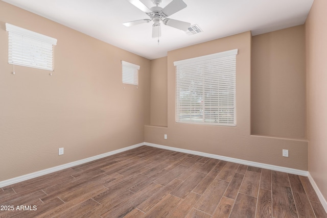 unfurnished room featuring visible vents, a ceiling fan, a healthy amount of sunlight, wood finished floors, and baseboards