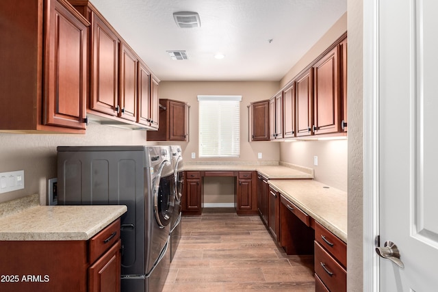 washroom featuring cabinet space, visible vents, separate washer and dryer, and light wood finished floors