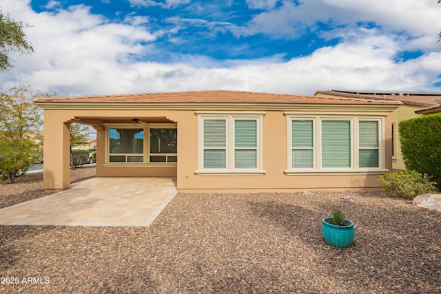 rear view of house featuring ceiling fan, a tiled roof, a patio area, and stucco siding