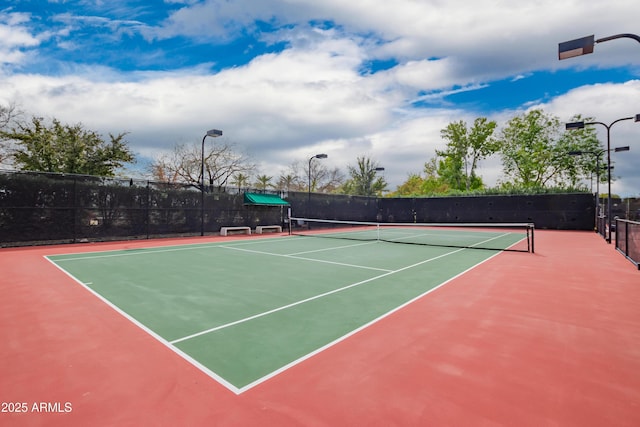 view of tennis court with community basketball court and fence