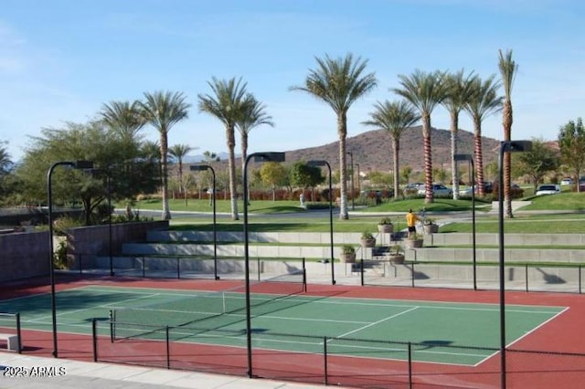 view of tennis court with fence and a mountain view