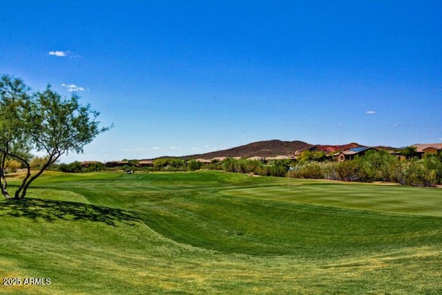 view of property's community featuring a lawn, golf course view, and a mountain view