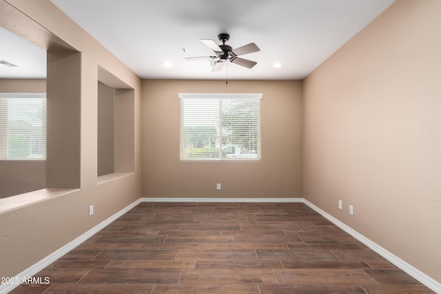 unfurnished room featuring ceiling fan, dark wood-type flooring, plenty of natural light, and baseboards