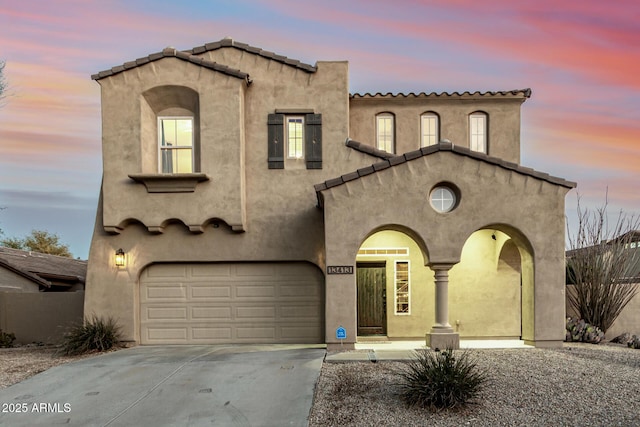 mediterranean / spanish house featuring driveway, a garage, fence, and stucco siding