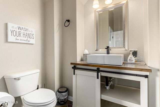 half bathroom featuring baseboards, toilet, and vanity