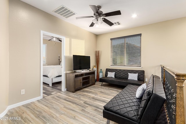living room featuring light wood finished floors, baseboards, visible vents, and ceiling fan
