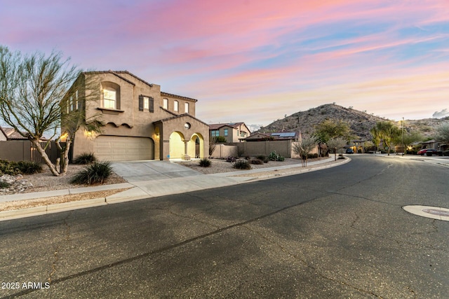 mediterranean / spanish-style home with stucco siding, fence, concrete driveway, and a mountain view