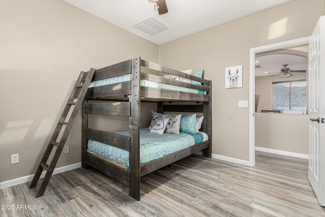 bedroom featuring a ceiling fan, baseboards, and wood finished floors