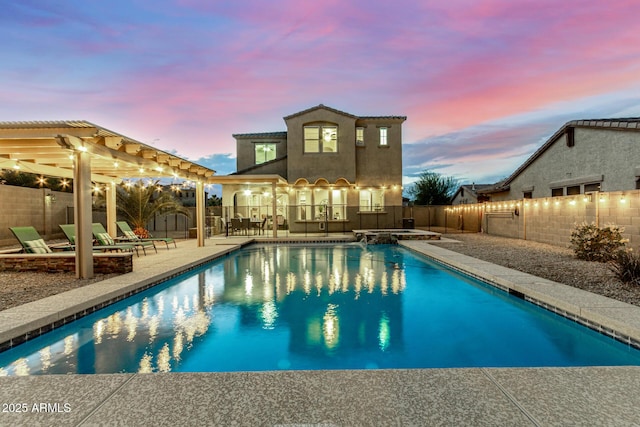 pool at dusk with a fenced backyard, a pool with connected hot tub, a patio, and a pergola