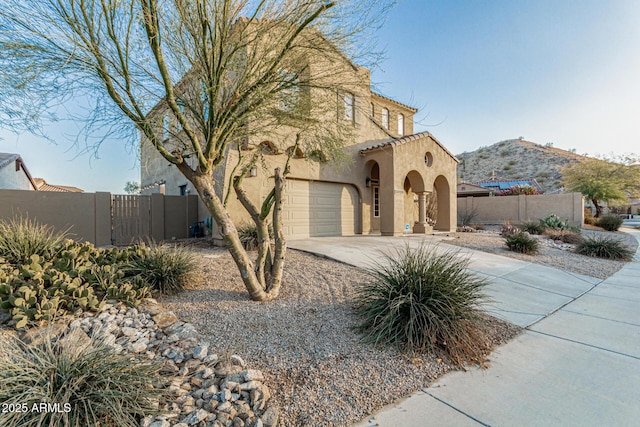 view of front of property with stucco siding, fence, an attached garage, driveway, and a gate