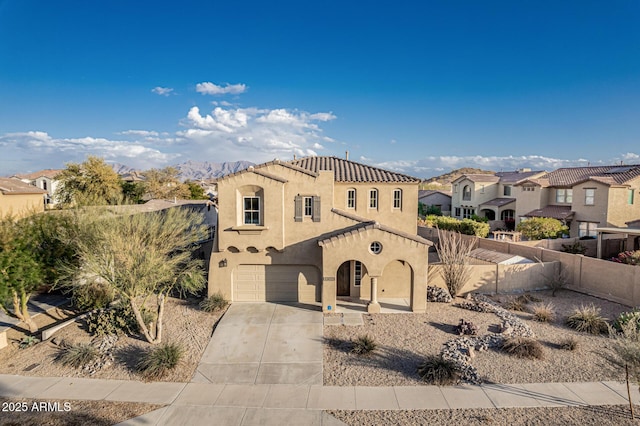 mediterranean / spanish-style house with concrete driveway, stucco siding, fence, an attached garage, and a residential view