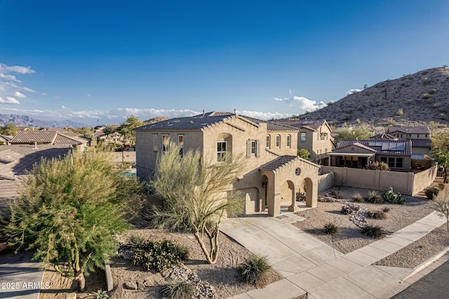 view of front of house featuring stucco siding, a tiled roof, driveway, a mountain view, and a garage
