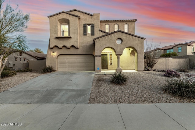 mediterranean / spanish-style home with concrete driveway, stucco siding, and fence