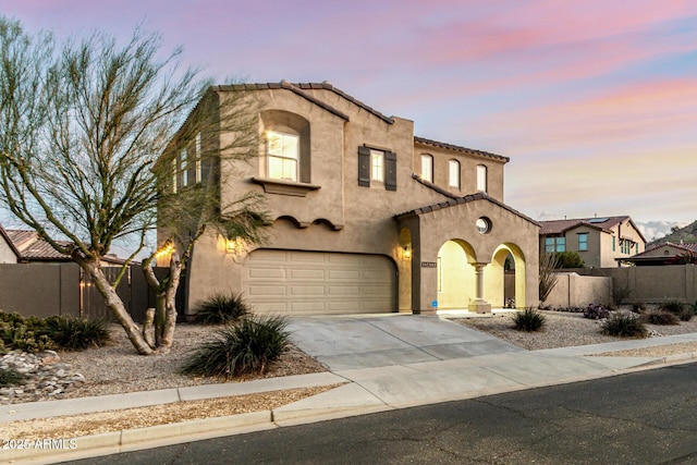 mediterranean / spanish-style house featuring driveway, stucco siding, fence, and a garage