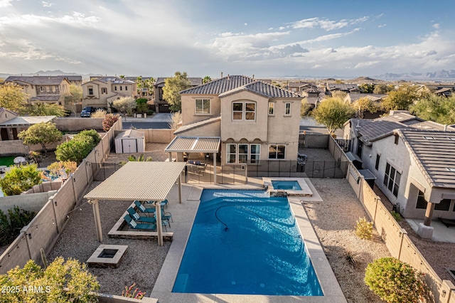 view of pool featuring a fenced backyard, a pool with connected hot tub, a residential view, and a patio