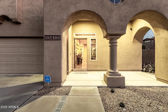 view of exterior entry featuring stucco siding and a garage