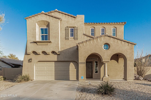 mediterranean / spanish-style house with stucco siding, an attached garage, and driveway