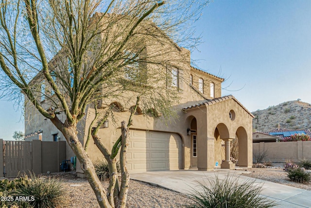 view of front facade with a tile roof, stucco siding, fence, and concrete driveway