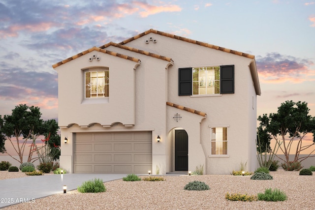 mediterranean / spanish-style house with stucco siding, driveway, an attached garage, and a tiled roof