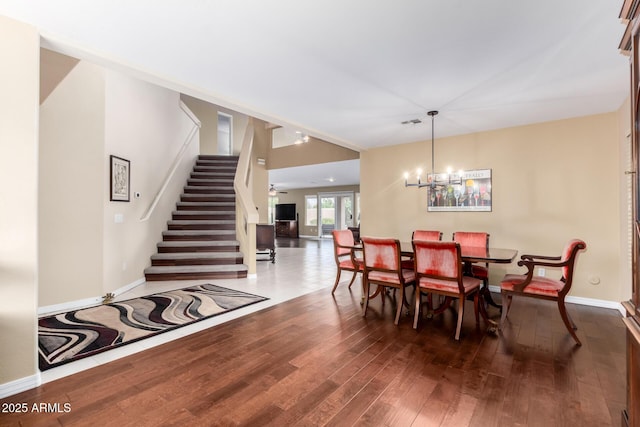 dining area with dark wood-type flooring and an inviting chandelier