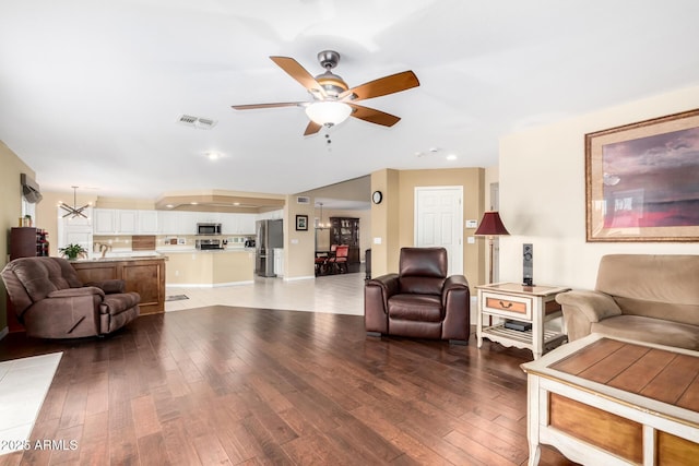 living room with ceiling fan with notable chandelier and hardwood / wood-style floors