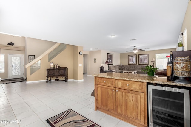 kitchen with ceiling fan, light tile patterned floors, wine cooler, and light stone counters