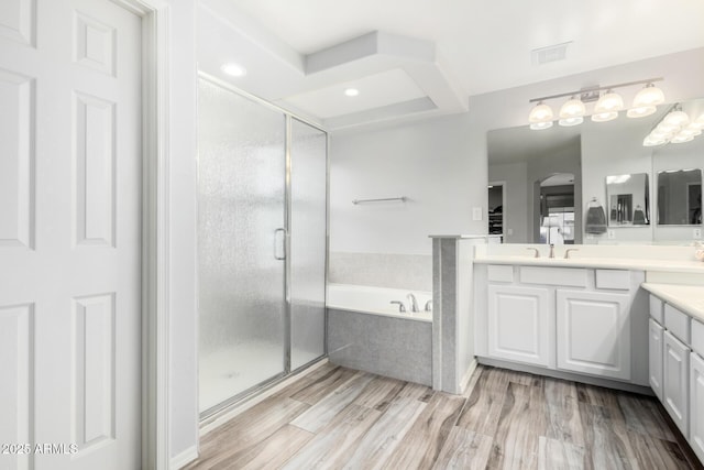 bathroom with hardwood / wood-style flooring, vanity, and plus walk in shower