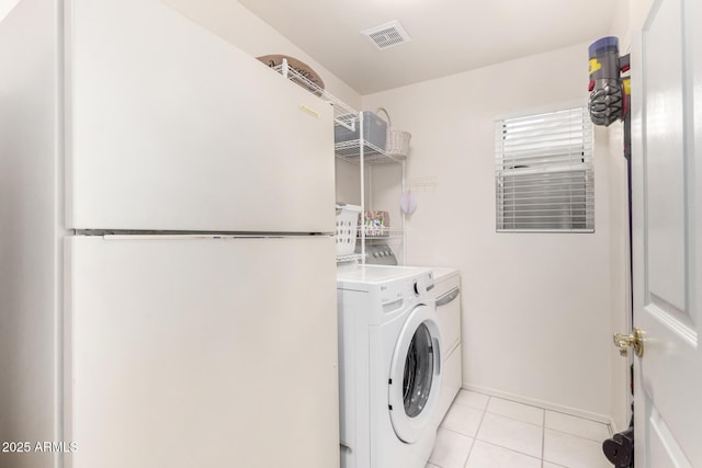 clothes washing area featuring washing machine and dryer and light tile patterned floors